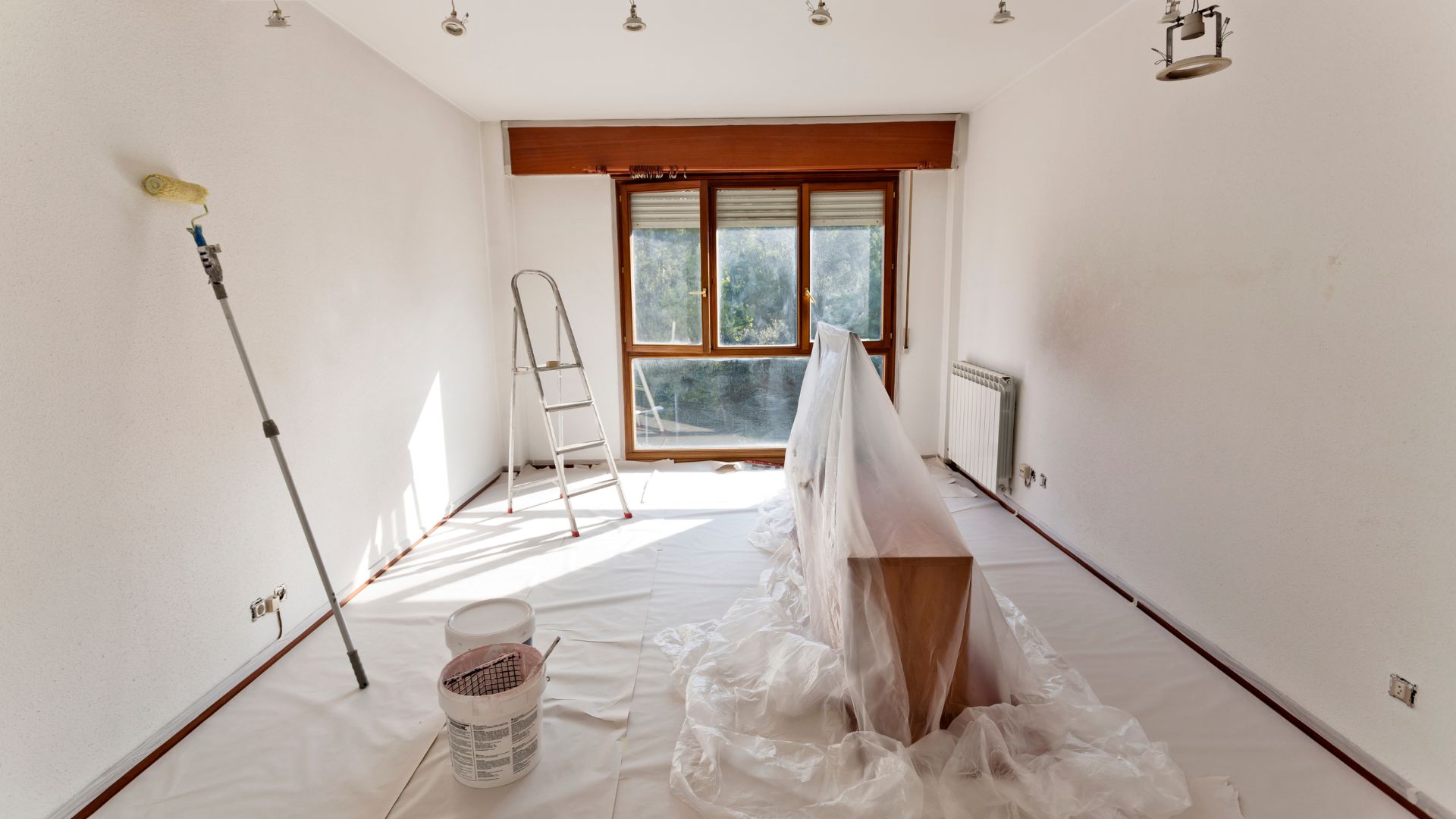 A room that has been painted white and has a ladder in the corner