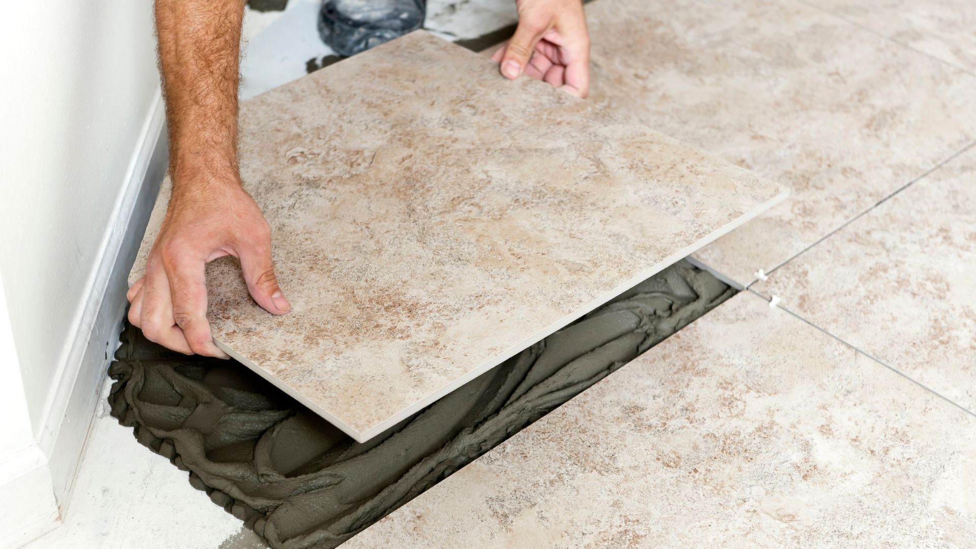 A man laying tile on the floor of a bathroom